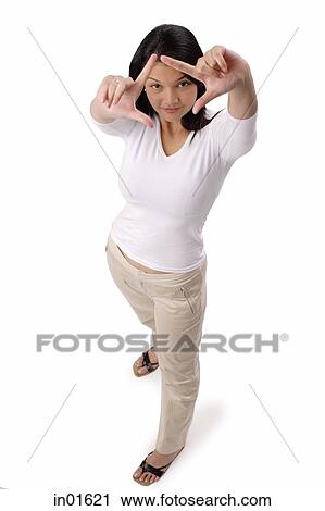 Stock Image - Woman looking at camera through finger frame. Fotosearch