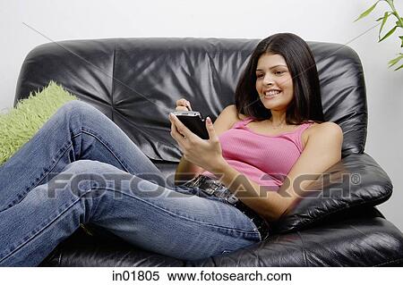 Woman lounging on armchair using PDA, smiling View Large Photo Image Stock Photography - Woman lounging on armchair using PDA, smiling. Fotosearch