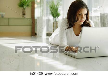 Woman lying on floor, using laptop View Large Photo Image Stock Photo - Woman lying on floor, using laptop. Fotosearch
