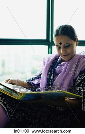 Stock Photo - Woman sitting at home going through photo album. Fotosearch
