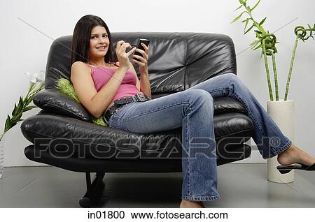 Woman sitting on armchair using PDA, smiling at camera View Large Photo Image Stock Image - Woman sitting on armchair using PDA, smiling at camera. Fotosearch
