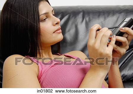 Woman sitting on armchair using PDA, side view View Large Photo Image Stock Image - Woman sitting on armchair using PDA, side view. Fotosearch