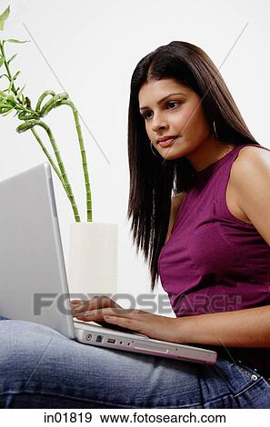 Stock Photo - Woman sitting, using laptop. Fotosearch