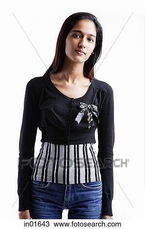 Stock Image - Woman standing against white background, looking at camera. Fotosearch