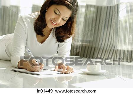 Woman writing in notebook, lying on floor View Large Photo Image Stock Photo - Woman writing in notebook, lying on floor. Fotosearch
