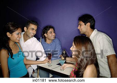 Stock Image - Young adults having drinks in bar. Fotosearch
