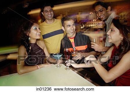 Young adults having drinks in club View Large Photo Image Stock Photograph - Young adults having drinks in club. Fotosearch