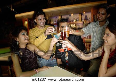 Stock Photo - Young adults in club, toasting with drinks. Fotosearch