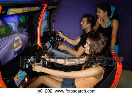 Young adults playing games in amusement arcade View Large Photo Image Stock Image - Young adults playing games in amusement arcade. Fotosearch