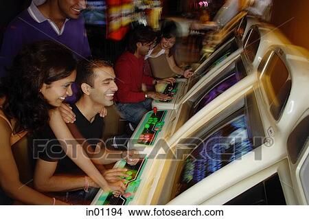 Young adults playing games in video arcade View Large Photo Image Picture - Young adults playing games in video arcade. Fotosearch