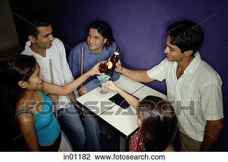 Stock Image - Young adults toasting with drinks. Fotosearch