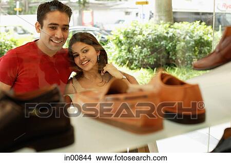 Young man and woman standing outside shoe shop looking at window display View Large Photo Image Picture - Young man and woman standing outside shoe shop looking at window display. Fotosearch