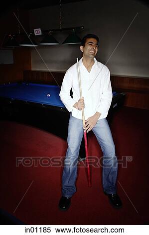 Young man leaning against pool table, smiling View Large Photo Image Stock Photography - Young man leaning against pool table, smiling. Fotosearch