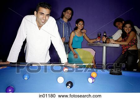 Young man standing at pool table, people in the background, all looking at camera View Large Photo Image Stock Image - Young man standing at pool table, people in the background, all looking at camera. Fotosearch