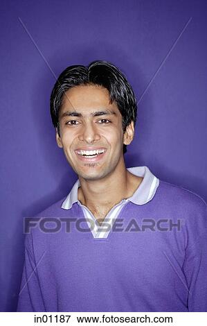 Stock Photo - Young man wearing purple shirt smiling at camera. Fotosearch