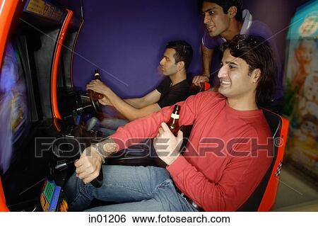 Young men in amusement arcade playing video games View Large Photo Image Stock Photograph - Young men in amusement arcade playing video games. Fotosearch