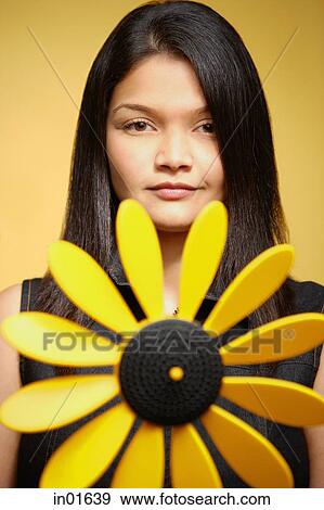 Stock Photo - Young woman against yellow background, pin wheel in front of her. Fotosearch