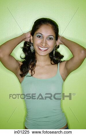 Stock Photography - Young woman in green tank top, against green background. Fotosearch