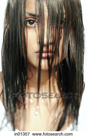 Stock Photo - Young woman looking at camera, long wet hair covering her face. Fotosearch