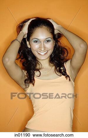 Stock Image - Young woman pulling hair back, hands on head. Fotosearch