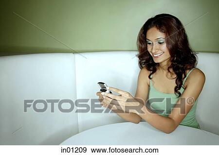 Young woman sitting in booth, looking at mobile phone View Large Photo Image Stock Photo - Young woman sitting in booth, looking at mobile phone. Fotosearch