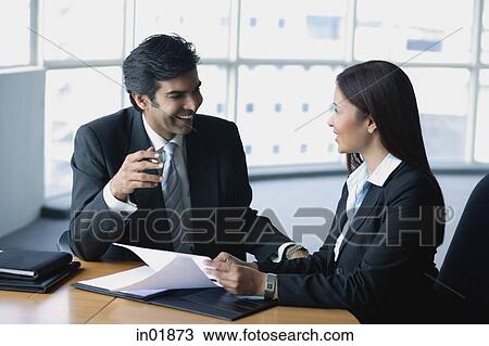 Businessman and businesswoman in office, having a discussion View Large Photo Image Stock Image - Businessman and businesswoman in office, having a discussion. Fotosearch