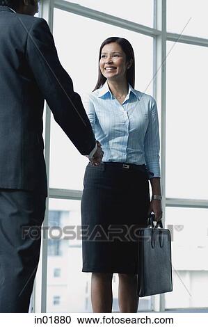 Stock Image - Businessman and businesswoman shaking hands. Fotosearch