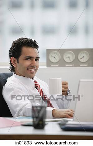 Businessman in office, holding coffee mug, smiling View Large Photo Image Stock Image - Businessman in office, holding coffee mug, smiling. Fotosearch