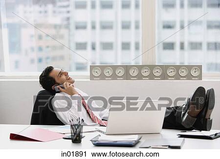 Businessman in office, using mobile phone, feet up on desk View Large Photo Image Stock Image - Businessman in office, using mobile phone, feet up on desk. Fotosearch