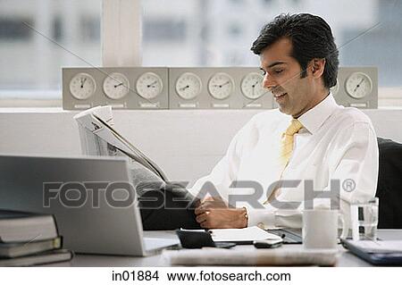 Businessman sitting in office, reading newspaper View Large Photo Image Picture - Businessman sitting in office, reading newspaper. Fotosearch