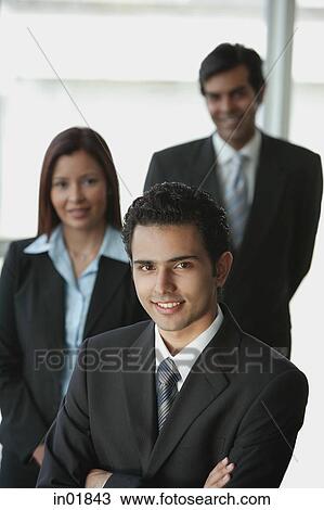 Businessman smiling at camera, other business people behind him View Large Photo Image Stock Image - Businessman smiling at camera, other business people behind him. Fotosearch