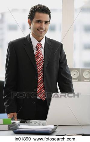 Businessman standing in office, looking at camera View Large Photo Image Stock Image - Businessman standing in office, looking at camera. Fotosearch