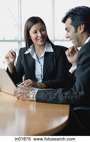 Stock Photography - Businesswoman and businessman having a discussion, using laptop. Fotosearch