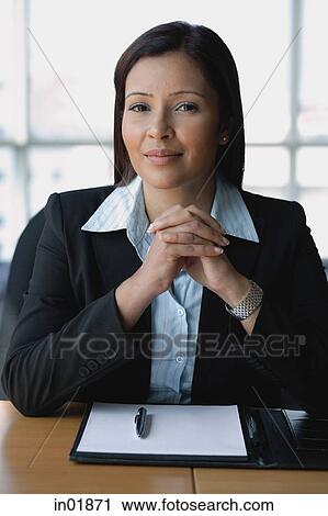 Stock Image - Businesswoman looking at camera, hands clasped. Fotosearch
