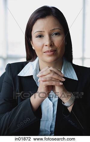 Stock Image - Businesswoman looking at camera, hands clasped, portrait. Fotosearch