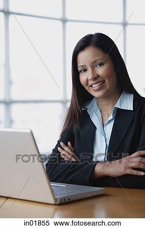 Businesswoman sitting in front of laptop, arms crossed, smiling View Large Photo Image Stock Photography - Businesswoman sitting in front of laptop, arms crossed, smiling. Fotosearch