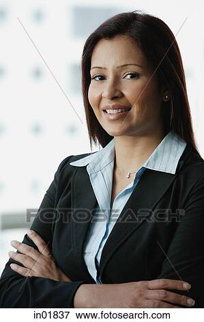 Stock Photo - Businesswoman smiling at camera, arms crossed. Fotosearch
