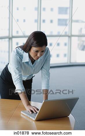 Businesswoman standing and using laptop View Large Photo Image Stock Photo - Businesswoman standing and using laptop. Fotosearch