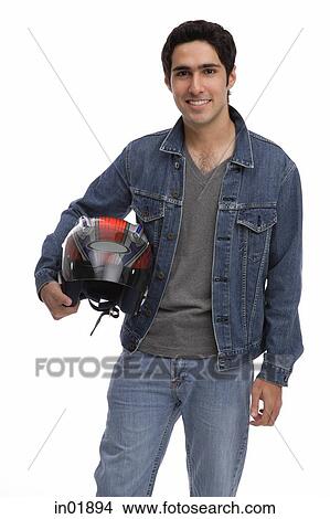 Picture - Man carrying motorcycle helmet, looking at camera. Fotosearch