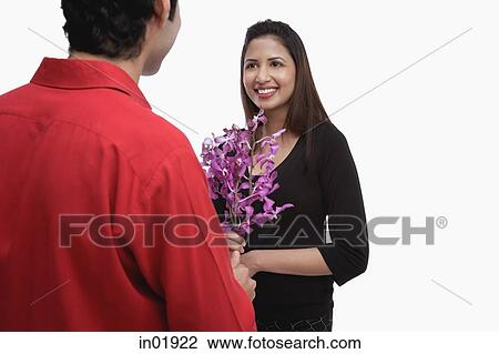 Woman holding flowers, smiling at man in front of her View Large Photo Image Stock Image - Woman holding flowers, smiling at man in front of her. Fotosearch