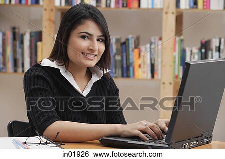 Woman in library, using laptop, looking at camera View Large Photo Image Stock Photograph - Woman in library, using laptop, looking at camera. Fotosearch