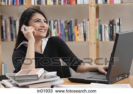 Woman in library, using mobile phone View Large Photo Image Stock Image - Woman in library, using mobile phone. Fotosearch