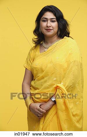 Woman in yellow sari standing against yellow background View Large Photo Image Stock Photo - Woman in yellow sari standing against yellow background. Fotosearch