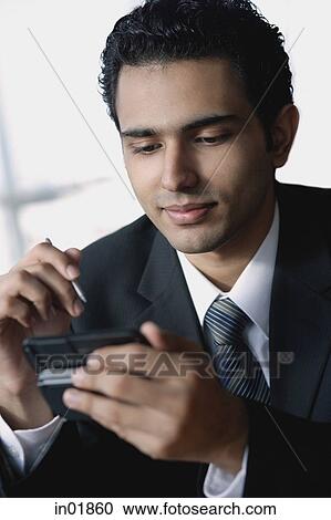 Young businessman using mobile phone, text messaging View Large Photo Image Stock Image - Young businessman using mobile phone, text messaging. Fotosearch