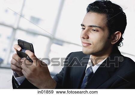 Young businessman using mobile phone, text messaging View Large Photo Image Stock Photo - Young businessman using mobile phone, text messaging. Fotosearch