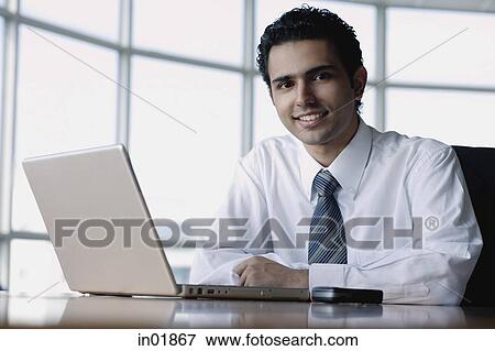 Young businessman with laptop, smiling at camera View Large Photo Image Stock Photo - Young businessman with laptop, smiling at camera. Fotosearch