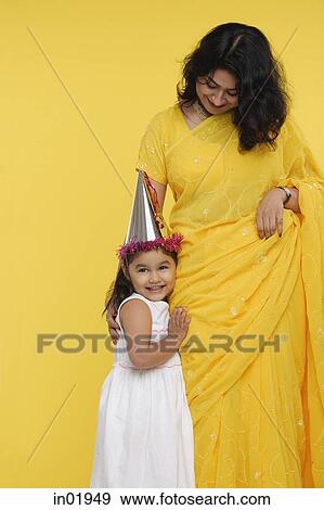 Young girl in white dress and party hat, standing next to her mother View Large Photo Image Stock Photo - Young girl in white dress and party hat, standing next to her mother. Fotosearch