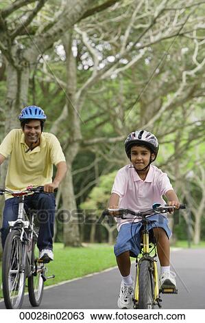 A father and son ride their bikes together View Large Photo Image Stock Image - A father and son ride their bikes together. Fotosearch
