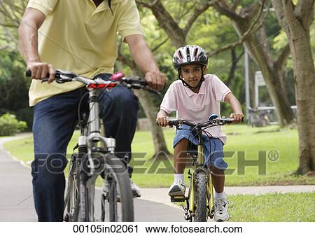 A father and son ride their bikes together View Large Photo Image Stock Image - A father and son ride their bikes together. Fotosearch