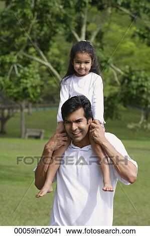 A father carries his daughter on his shoulders as they both look at the camera View Large Photo Image Stock Image - A father carries his daughter on his shoulders as they both look at the camera. Fotosearch